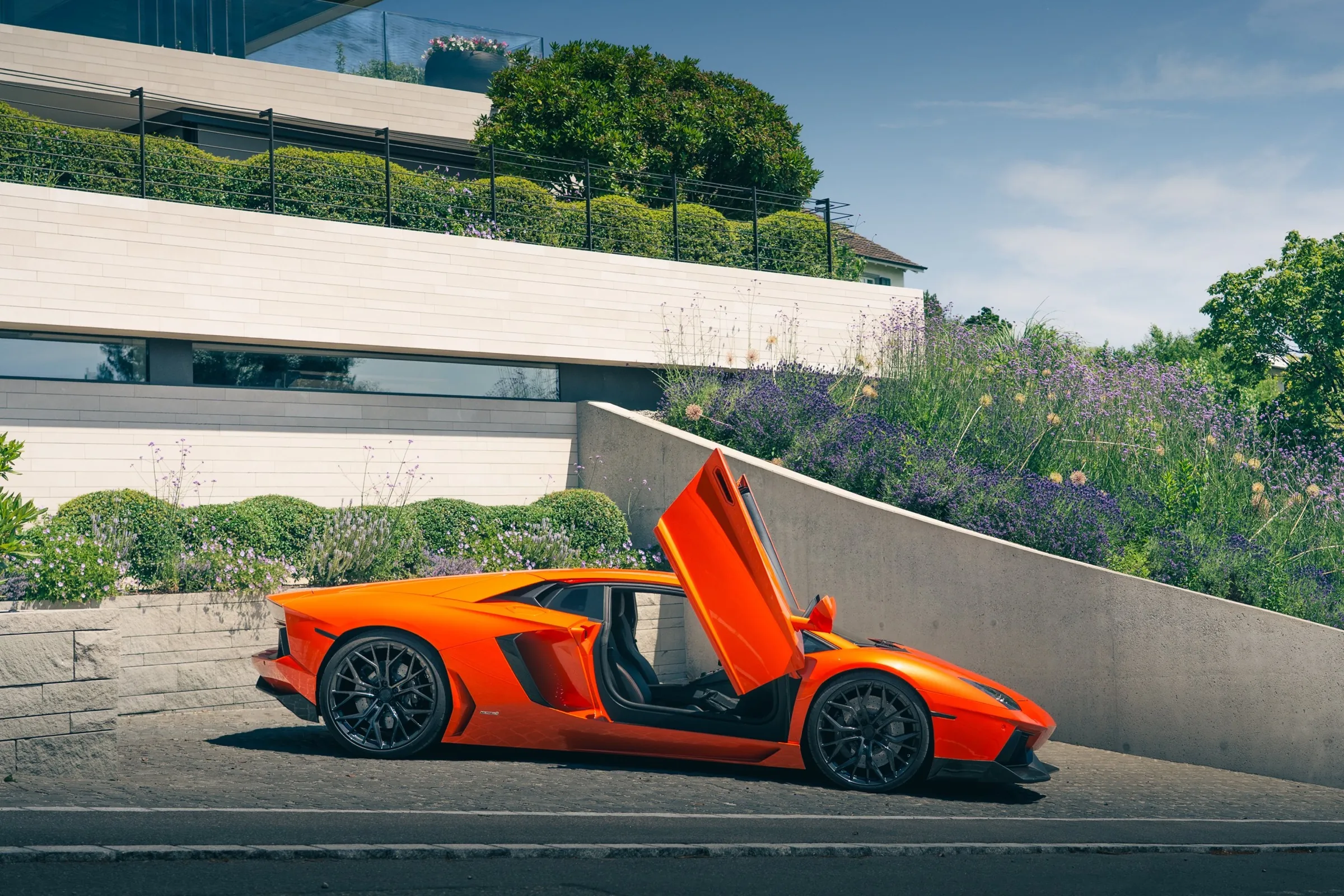 Lamborghini Aventador mit geöffneten Türen vor einer modernen Villa